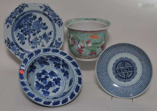 Lot of four porcelains. China. 19th to 20th century. To include: A jardinière with Famille Rose decoration of children and three pieces of underglaze blue: A basin, a bowl and a plate. Hairlines and chips. Largest- 12