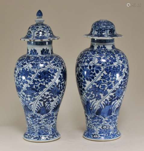 Pair of porcelain covered jars. China. K'ang Hsi period. (1662-1722). Moulded bodies. Underglaze blue decoration of flowers. Artemesia leaf mark. Fritting and chips to the covers, one with a missing finial. 12