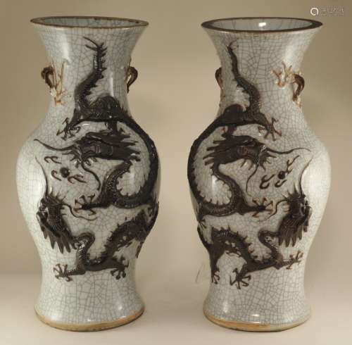 Pair of porcelain vases. China. Early 20th century. Baluster form with prunus handles. Relief decoration of dragons and cranes, burnt brown in colour on a crackled white ground. Engraved K'ang Hsi mark on the base. 17