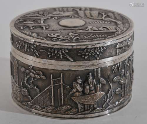Chinese Export silver box. 19th to early 20th century. Cylindrical form. Repousse decoration of people in a garden scenes on a fish roe ground. Signed K.W.  4