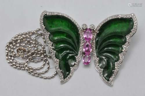 18k white gold butterfly brooch, featuring jade, pink sapphires, and diamonds. Overall size is 54 x 43mm. Jade carved wings have been tested by GIA as translucent green undyed jadeite, report #2203013111. Three oval pink sapphires, largest measuring approximately 7.5 x 5 mm, smallest 5.6 x 4.2mm. Two round brilliant diamonds set into eyes, approximately 3mm each. Round briliant diamonds surround the entire border of the brooch. Total weight is 15.1 grams. Hallmarked 750.