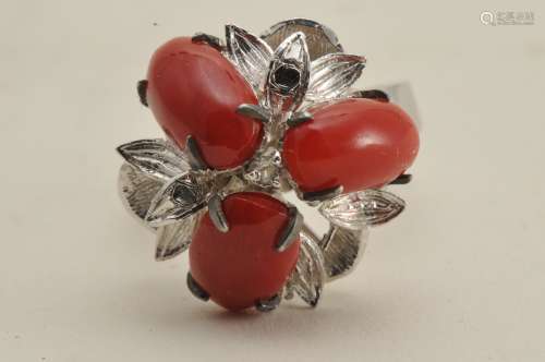 10 k white gold coral and diamond ring. 3 deep- red oval shaped coral beads, approximately 11 x 6 mm each. One small diamond, single-cut, in cnter of mounting. Approximately .01 ct. Finger size 7. Hallmarked 10k.