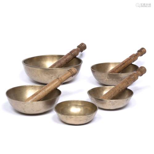 Five Tibetan singing bowls together with four wooden batons largest 21cm across Provenance: The