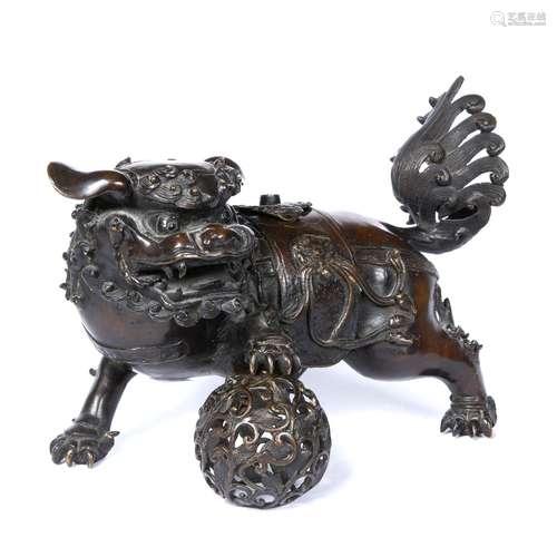 Bronze figure of a Buddhist lion Chinese cast standing with its head turned, resting with its paw on