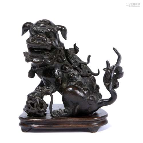 Bronze temple dog Chinese, Ming (1368-1644) in a prone position with one paw on a ball, with a later