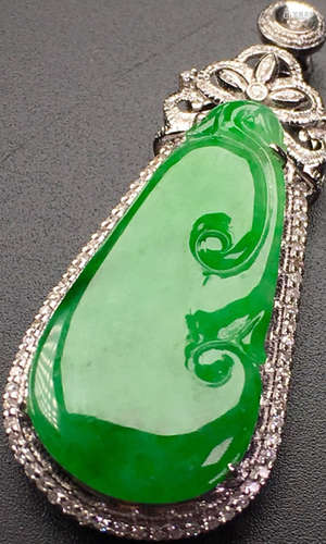 A GREEN JADEITE CARVED AUSPICIOUS PATTERN PENDANT