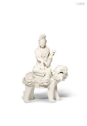 A CHINESE BLANC DE CHINE FIGURE OF GUANYIN AND A LION DOG 20TH CENTURY She sits in lalitasana on the