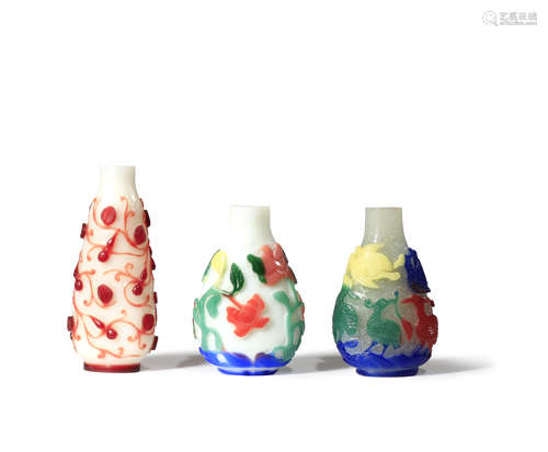 THREE CHINESE OVERLAY GLASS SNUFF BOTTLES C.1900 One carved through red glass to a white ground with