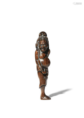 A JAPANESE WOOD NETSUKE MEIJI 1868-1912 Depicting a tall standing man with a large octopus on his