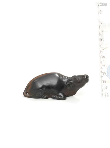 Attributed to Kanman (1793-1859), Iwami Province, early 19th century A large kurogaki (black persimmon) wood netsuke of a recumbent ox