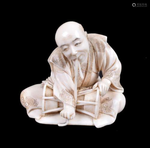 ϒ HOMIN: A Japanese carved ivory Okimono depicting a drummer seated cross-legged on a mat