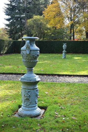 A pair of painted lead twin handled urns and pedestals