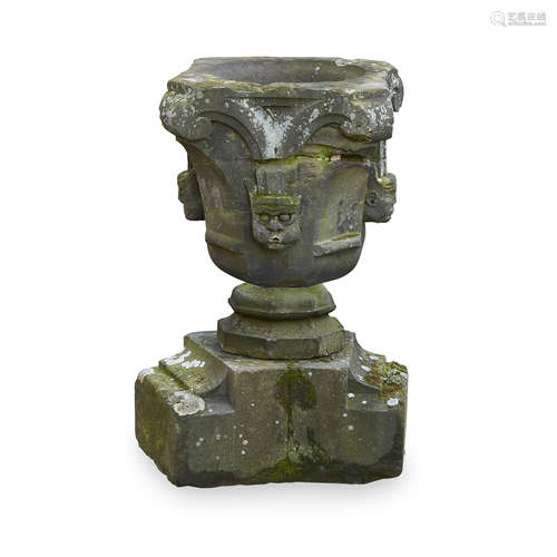 CARVED STONE URN OR FONT 17TH CENTURY OR EARLIER of octagonal bell form, the sides carved with masks