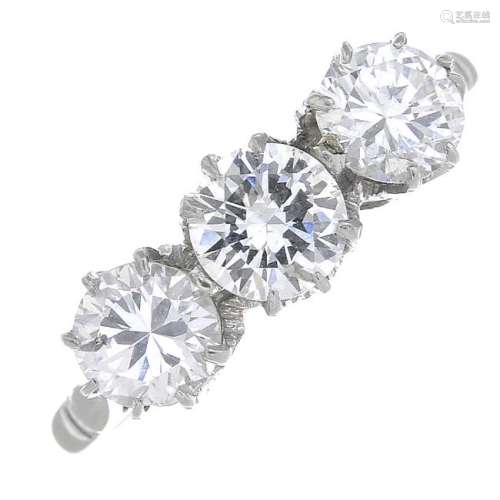 A diamond three-stone ring. The brilliant-cut diamond,