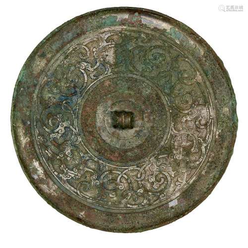 A Chinese bronze circular mirror, Warring States period, flat cast with intertwined scrolling