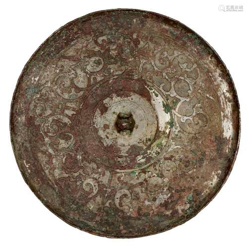 A Chinese bronze circular mirror, Warring States period, flat cast with intertwined scrolling
