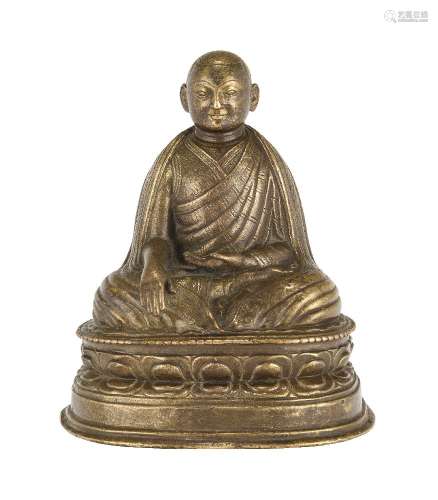 A Tibetan bronze figure of a lama, 15th century, with right hand in bhumisparshamudra, his left hand