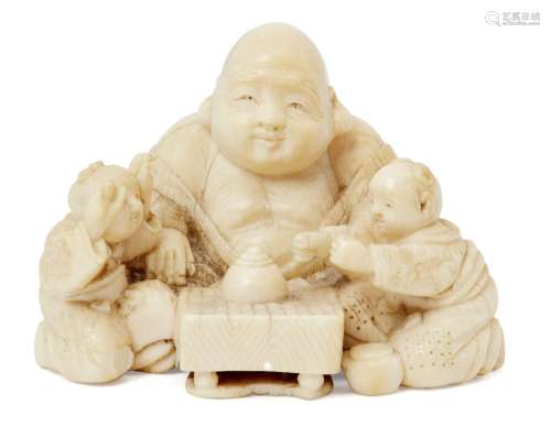 A Japanese ivory netsuke, 19th century, carved as Hotei and two boys playing a board game, 4.5cm
