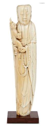 A Chinese ivory figure of Guanyin, late Ming dynasty, carved standing, holding a child who is