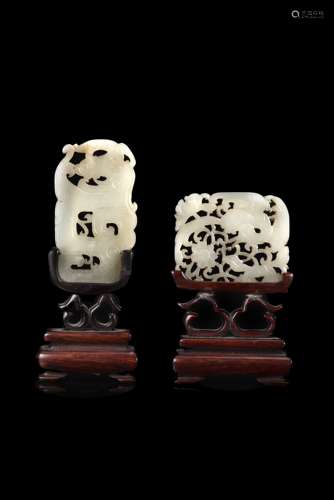 Two carved and pierced celadon jade plaques, wood base (defects)China, 20th century(h. max 7 cm.)