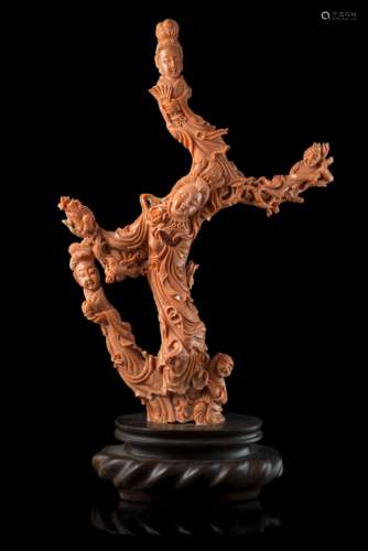 A coral carving of ladies wearing long robes, children and birds perched on flowering branches (