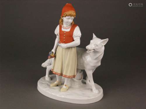 Porcelain group ''Little Red Riding Hood'' - Fraureuth porcelain factory, an appropriately<br />dressed fairy tale figure with basket and picked flowers in her hands, looking at the big wolf behind her, polychrome onglaze painting, slightly rubbed at the top of the cap, monogrammed on plinth ''MBI '', marked in unglazed ground: green manufactory stamp 1909-1923, pressed No.9, painted decor number: 23/453 and 39, H.ca.24cm