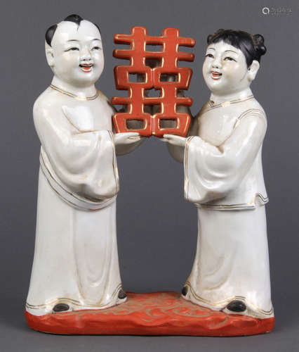 Chinese porcelain figural group, of a male and female holding a shuangxi plaque, base marked 'Wan