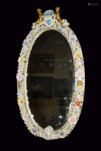 A Continental Porcelain Oval Mirror Fully Covered with Flowers and Two Angels on the Top