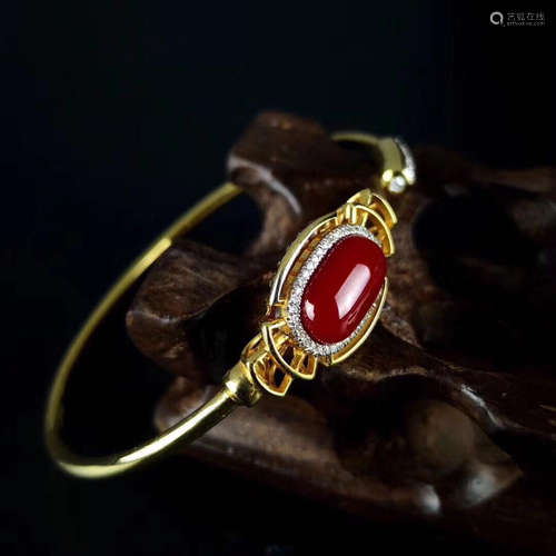 AN 18K GOLD BANGLE WITH EGG SHAPE AKA TYPE RED CORAL STONE