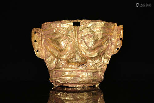 A GOLD FOIL COVERED MASK WITH CELESTIAL DESIGN