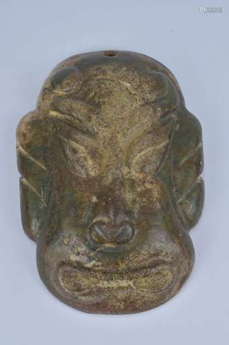 A large archaic style stone mask pendant. 9cm width