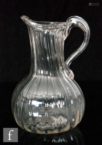 An early to mid 19th Century clear crystal glass jug of globe and shaft form with fine vertical