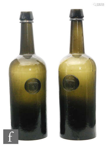 A pair of 19th Century Ricketts style deep green glass bottles with applied seals with an unknown