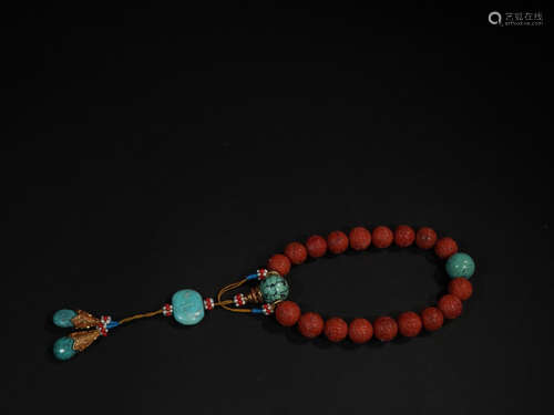 AN EIGHTEEN BEADS RED WOOD BRACELET WITH TURQUOISE STONE