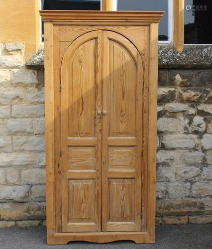 A Large Scrubbed Pine Corner Cupboard: Gothic shaped doors open to reveal three shelves, approx 100 x 43 x 208 cms