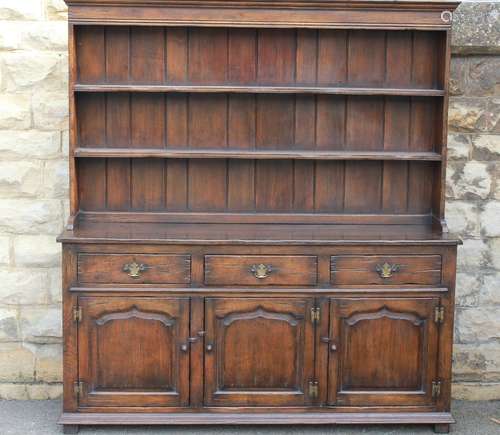 An Oak Dresser: the dresser having three short drawers, three single shelf cupboards beneath and two plate racks above, approx 168w x 46d x 183h cms