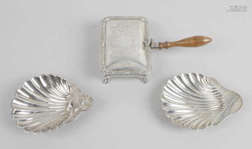 An Edwardian silver shell butter dish raised upon three ball feet,