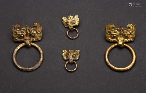 A GROUP OF FOUR GILT BRONZE MASK AND RING HANDLES