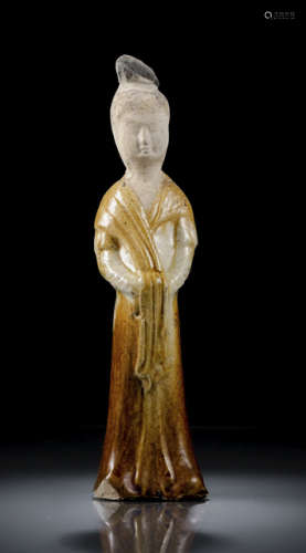 A BEIGE AND AMBER GLAZED EARTHENWARE MODEL OF A STANDING COURT LADY