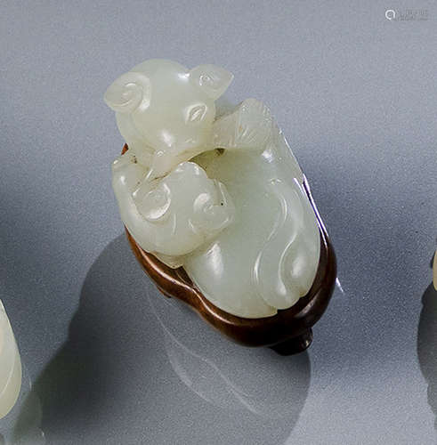 A LIGHT GREEN JADE CARVING OF A RECUMBENT CAT AND IT'S YOUTH