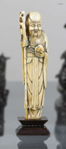 A WELL CARVED IVORY MODEL OF STANDING SHOULAO WITH PEACH AND STAFF