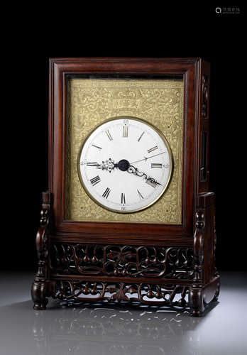 A TABLE CLOCK ON A CARVED WOOD STAND