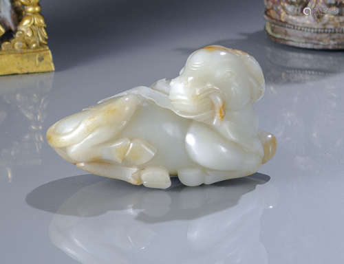 A LIGHT GREEN AND CARAMELJ JADE CARVING OF A RECUMBENT OX WITH MILLET BRANCH