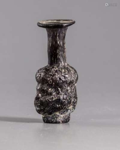 A Roman moulded purple glass head flask
