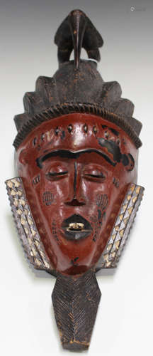 A Senufo carved and painted wooden mask, Ivory Coast, the braided coiffure with hornbill surmount,