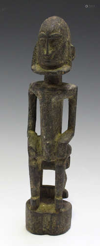 A Dogon carved wooden ancestor figure, Mali, modelled as a male seated on a stool, with an overall