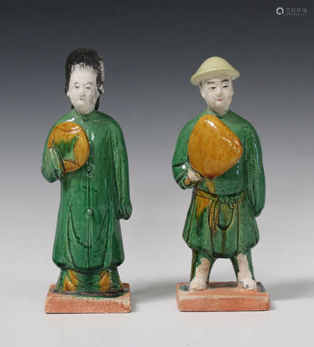 A pair of Chinese sancai glazed pottery figures of attendants, Ming dynasty, each modelled