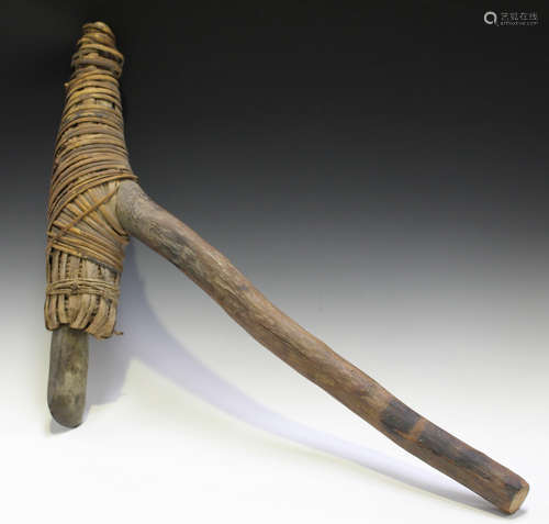 A Papua New Guinea digging axe, the carved stone head rattan bound to a long wooden handle with