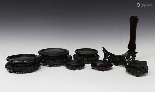 A collection of eighteen Chinese carved wood stands, 19th century and later, of various shapes and