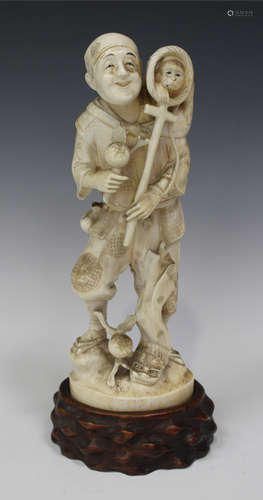 A Japanese carved ivory okimono figure of a monkey trainer, Meiji period, modelled standing with the